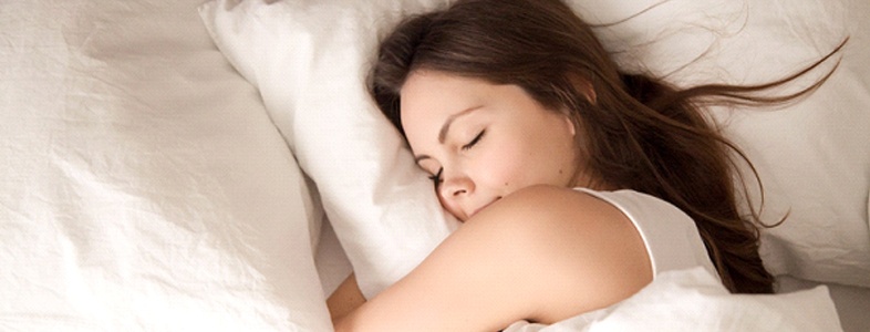 A young woman asleep in bed, getting adequate sleep after receiving sleep apnea therapy in Fort Worth