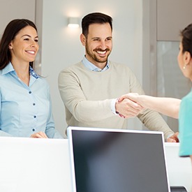 Smiling man and woman at reception desk