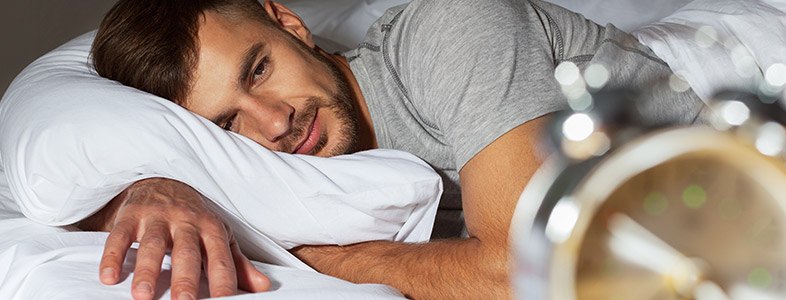 Man in bed staring at the clock