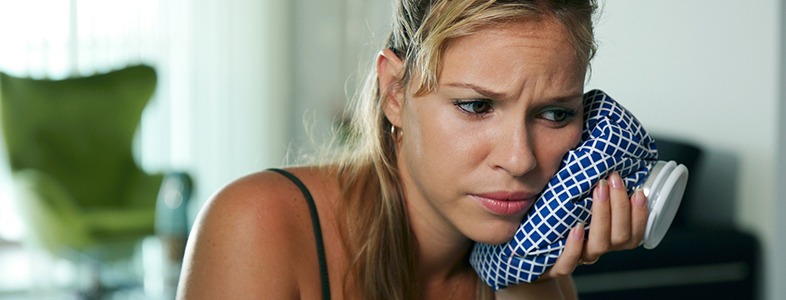 Woman holding ice pack to cheek