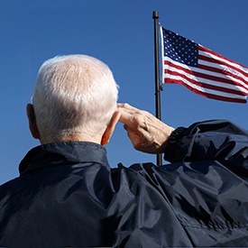 Older veteran saluting an American flag