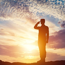 Silhouette of a veteran saluting with a beautiful sunset background