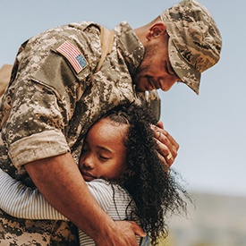 Veteran hugging his young daughter holding an American flag