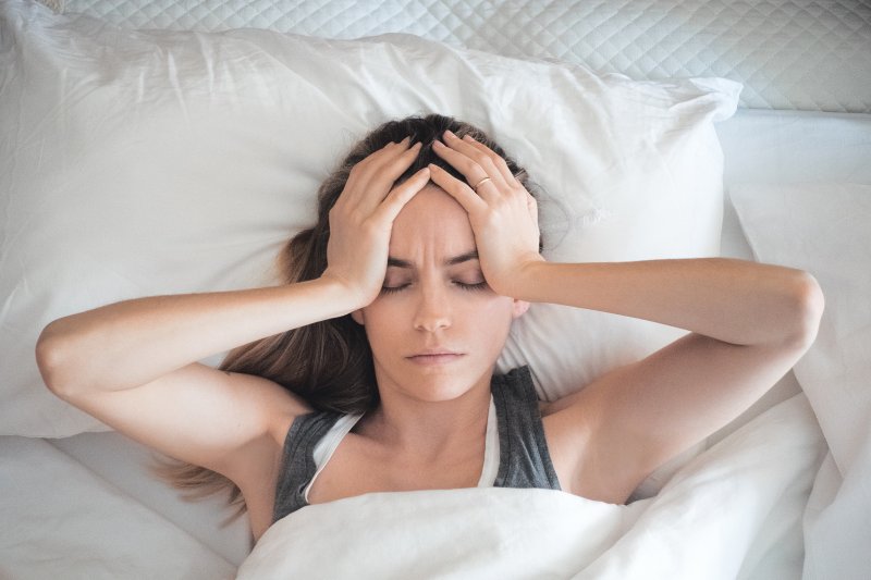 Woman with sleep apnea awake in bed with headache