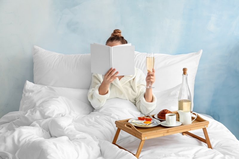 Woman having a glass of wine while reading in bed