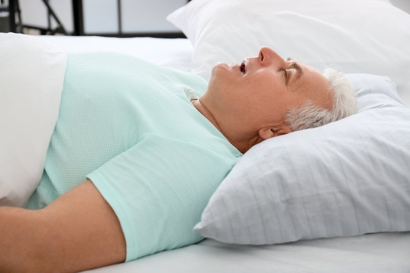 Man lying on back in bed mouth breathing