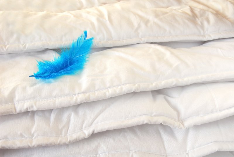 Pile of weighted blankets with a blue feather on them
