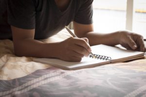 Man lying on bed, recording notes in sleep diary