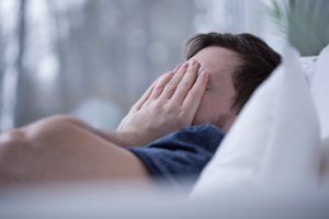 Man in bed, exhausted because of sleep apnea