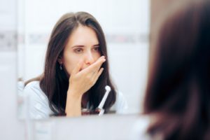 Woman covering mouth, concerned about sleep apnea and gum disease