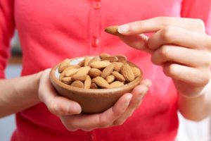 Woman eating almonds, a food that can promote high-quality sleep