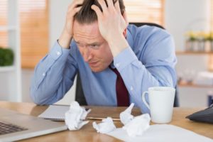 Man in front of computer, struggling to concentrate