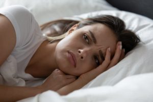 young woman anxious in bed 