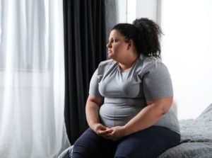 Overweight woman sitting on her bed