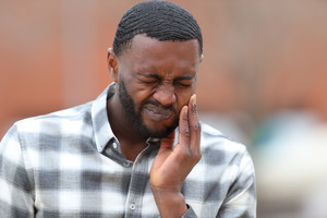 Man with TMJ disorder rubbing jaw due to pain