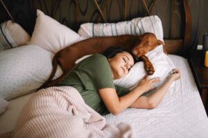 Woman and her dog sleeping on bed 