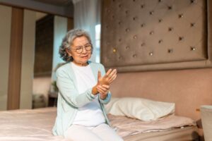 Woman sitting on her bed, struggling with RA pain
