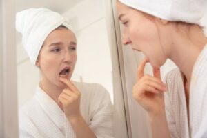 Concerned woman looking at her gums in mirror 