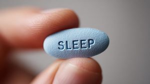 Sleeping pill between person’s thumb and forefinger